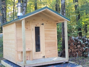 A wooden cabin with a pitched roof, a door, and a chimney.