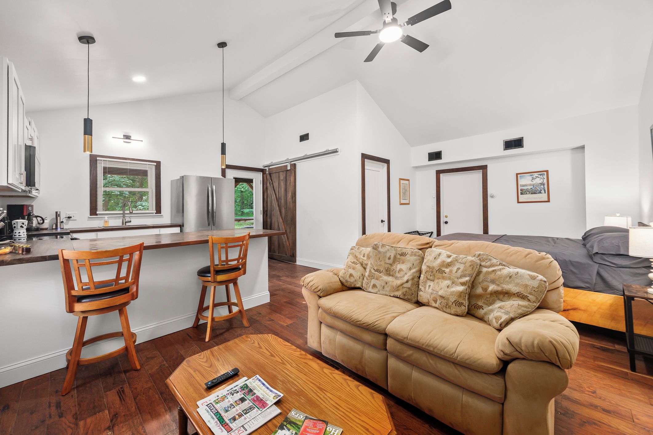 A modern kitchen with a dining area, a sofa, and a ceiling fan.