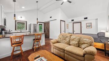 A modern kitchen with a dining area, a sofa, and a ceiling fan.