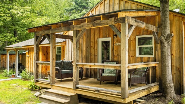 A wooden cabin with a porch, a shop sign, and outdoor seating.