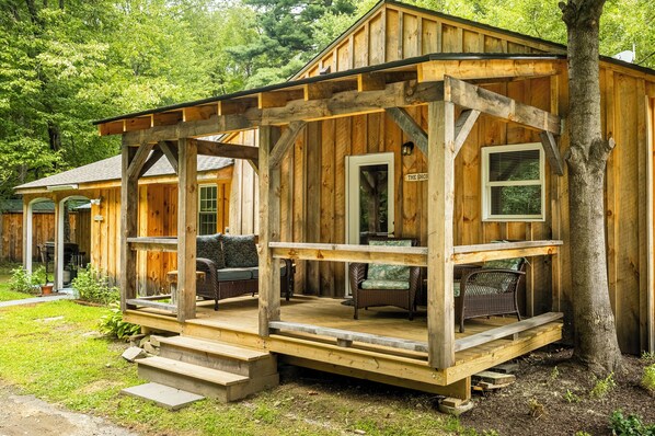 A wooden cabin with a porch, a shop sign, and outdoor seating.