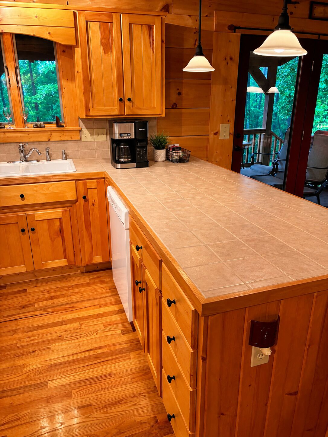A wooden kitchen with a large island, a coffee maker, and a sink.