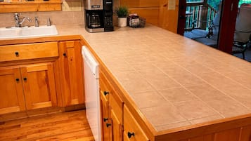 A wooden kitchen with a large island, a coffee maker, and a sink.