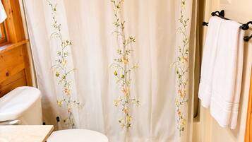 A bathroom with a toilet, a sink, and a shower curtain with floral embroidery.