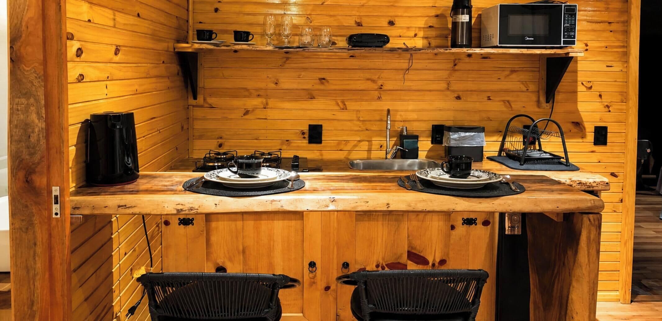 A compact kitchen with wooden walls, a microwave, a coffee maker, and a sink.