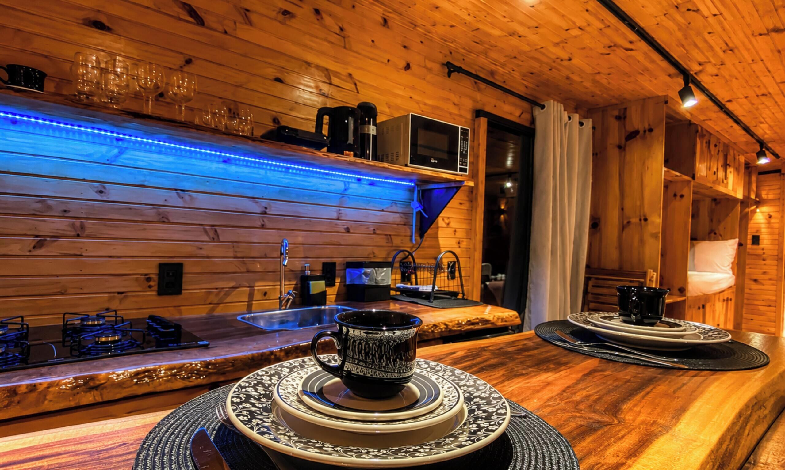 Un intérieur en bois comprenant un espace bar équipé d’un évier, d’un four à micro-ondes et d’un coin café.