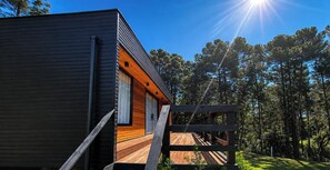 Una cabaña moderna con terraza de madera y garaje.