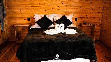 A wooden cabin-style room with a bed, two nightstands, and a swan-shaped towel arrangement.