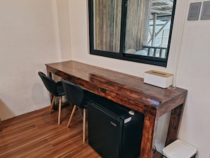 A compact room with a wooden desk, two chairs, a black refrigerator, and a window with curtains. - Basilia Guest House (Santa Fe)