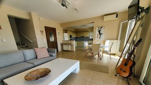 Ein modernes Wohnzimmer mit Sofa, Couchtisch und einer an der Wand angelehnten Gitarre.