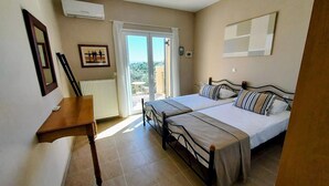 Ein Schlafzimmer mit einem Bett, einem Schreibtisch und Blick durch eine Glastür.