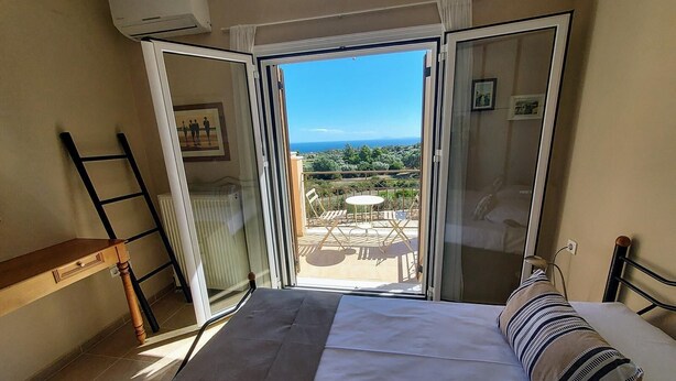 Ein Schlafzimmer mit Bett, Stuhl, einer Leiter und einem Balkon mit Tisch und Stühlen.