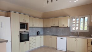Eine moderne Küche mit hellen Holzschränken, Backofen, Mikrowelle und Geschirrspüler.