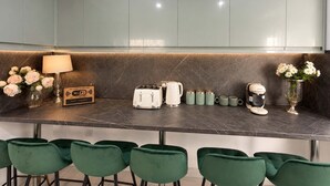 A modern kitchen with a marble countertop, green chairs, and a Wi-Fi sign. - Luxury 6BR Family Home 3 Bath With Hot Tub Fast WiFi (Cardiff)