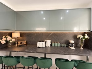 A modern kitchen with a marble countertop, green chairs, and a Wi-Fi sign. - Luxury 6BR Family Home 3 Bath With Hot Tub Fast WiFi (Cardiff)