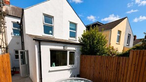 A residential property with a hot tub, a wooden fence, and a garden with various plants. - Luxury 6BR Family Home 3 Bath With Hot Tub Fast WiFi (Cardiff)