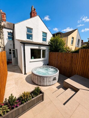 A residential property with a hot tub, a wooden fence, and a garden with various plants. - Luxury 6BR Family Home 3 Bath With Hot Tub Fast WiFi (Cardiff)