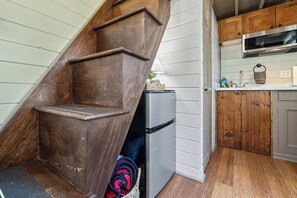 Una cocina con gabinetes de madera, un refrigerador y un microondas.