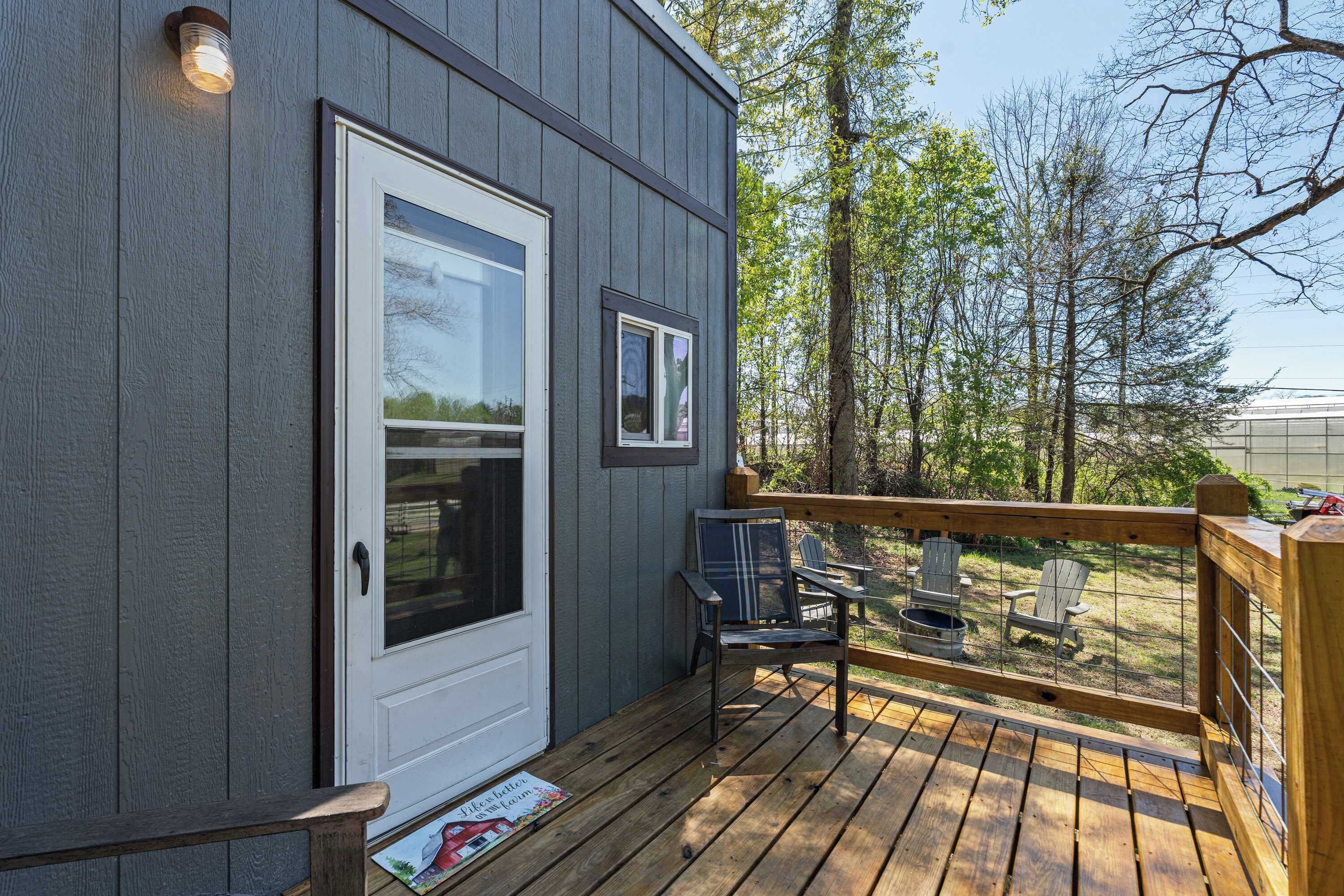 A wooden deck with a door and windows, surrounded by trees.