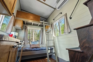 A compact, well-organized cabin with a bunk bed, a small kitchenette, and a window providing a view of the outdoors. - NEW 2 bed tiny home on the farm (Asheville)