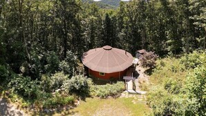 Un edificio circular con techo rojo rodeado de un bosque denso.