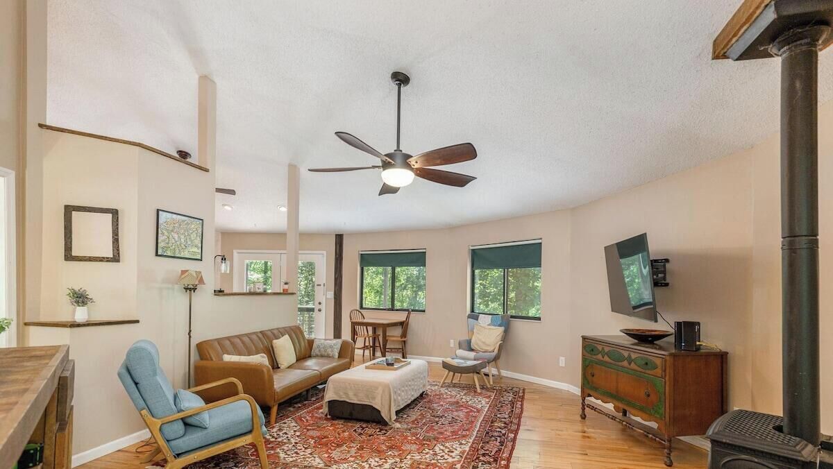 Un salon spacieux doté d’un ventilateur de plafond, d’une cheminée, d’un téléviseur et d’un coin repas.