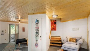 Una habitación con cama, una silla, una escalera y una puerta con un adorno colgante.