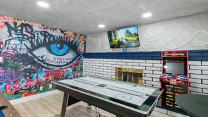 Ein Zimmer mit Tischfußball, Fernseher an der Wand und Graffiti-Kunst.