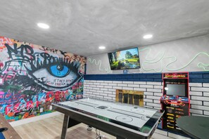 Ein Zimmer mit Tischfußball, Fernseher an der Wand und Graffiti-Kunst.