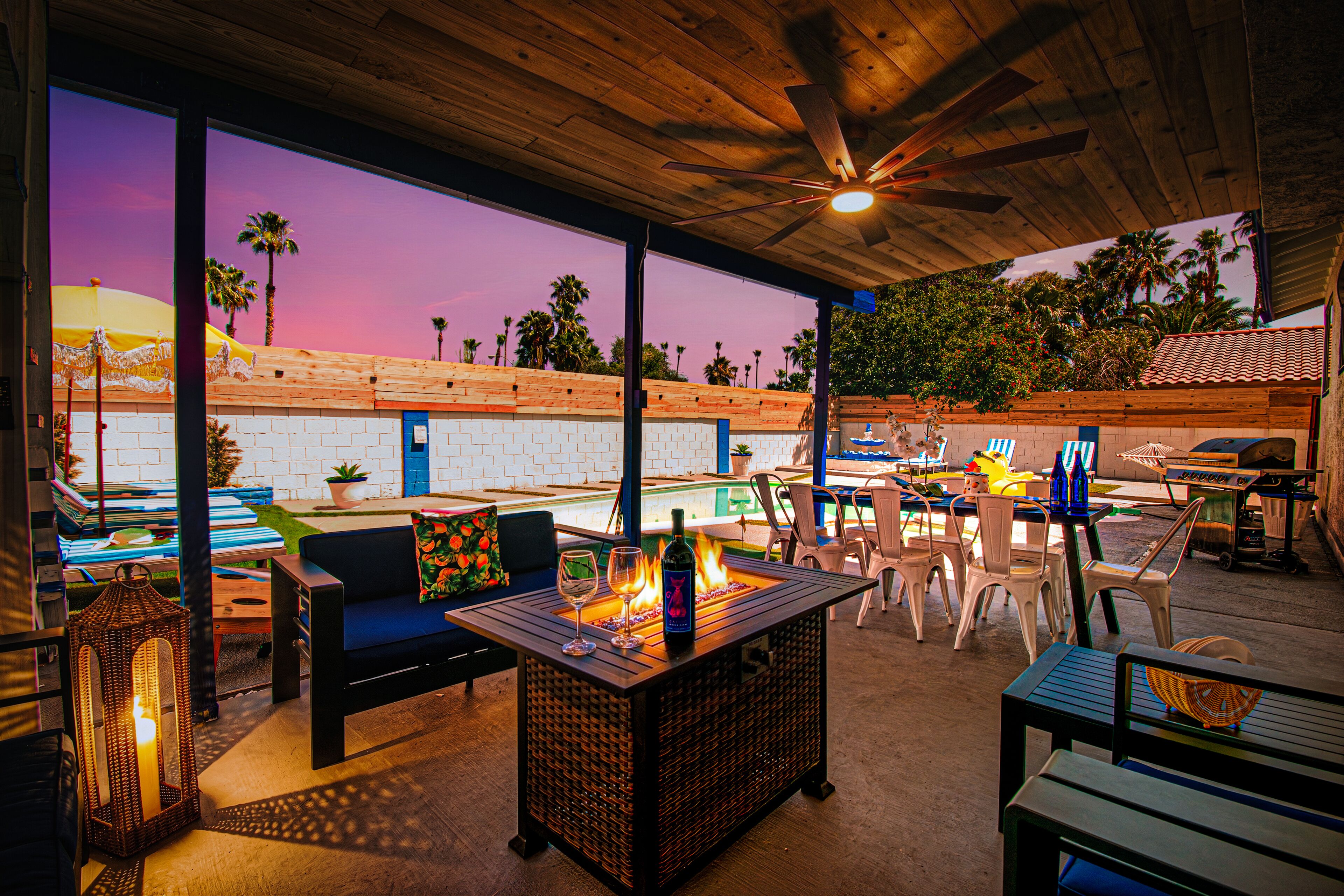 An outdoor patio with seating, a fire feature, and a view of palm trees.