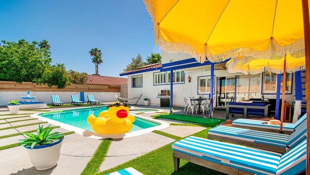 Ein Poolbereich mit einer gelben Schwimmenten, Liegestühlen und einer Grillgelegenheit.