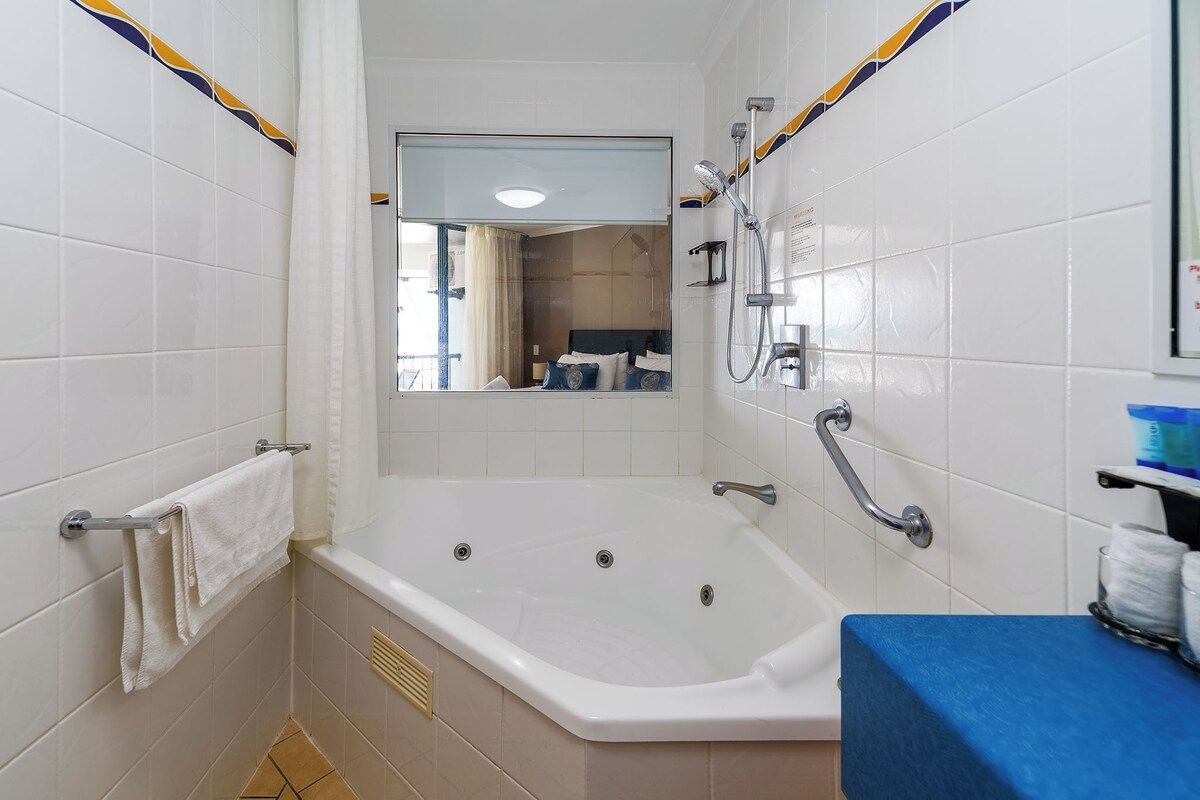 Ein Badezimmer mit einer Badewanne, einer Dusche, einem Handtuchhalter und einem Spiegel.