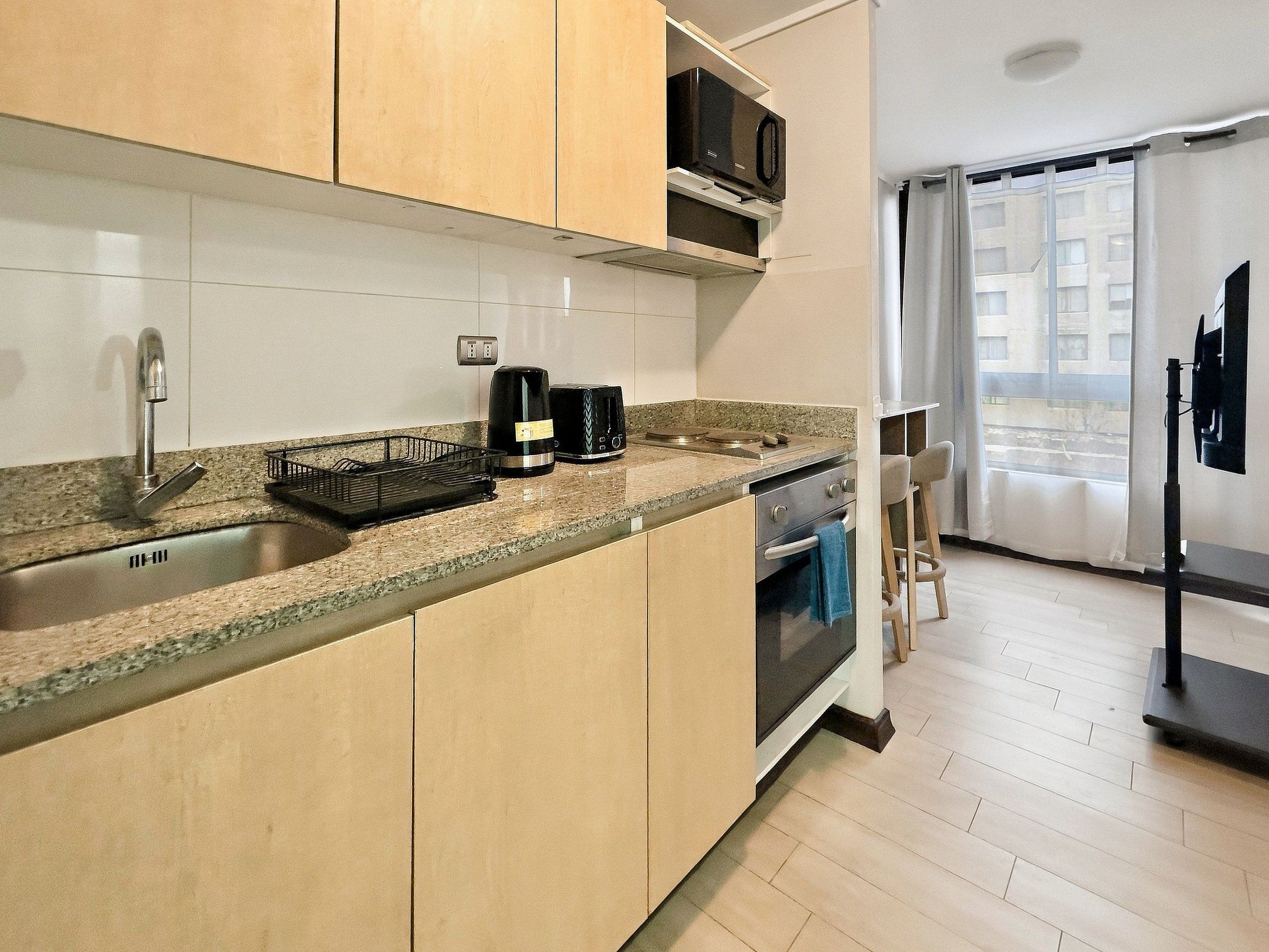 A compact kitchen with a built-in microwave, a coffee maker, and a toaster.