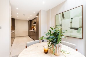 A modern dining area with a round table, a candle, and a potted plant. - Luxury Three-Bed Chelsea Townhouse (London)
