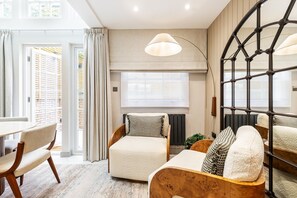 A modern living room with a sofa, armchair, and a dining table. - Luxury Three-Bed Chelsea Townhouse (London)
