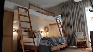A bedroom with a bunk bed, a ladder, a bedside table with a lamp, a chair, and a large window with curtains. - Luxury penthouse with a private terrace and ocean views | Ayuuk (Cruz de Huanacaxtle)