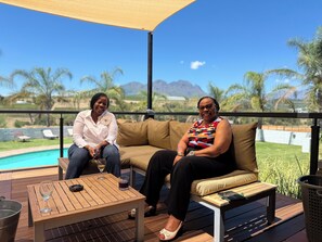 Two people seated on a sofa with a pool and mountains in the background. - the MANOR house by Kana Guest Farm (Stellenbosch)