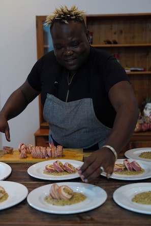 A person preparing food, specifically bacon-wrapped items, on a wooden table with multiple plates. - the MANOR house by Kana Guest Farm (Stellenbosch)