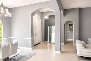 A spacious living area with a white sofa, a dining table with chairs, and a chandelier. - Luxury Home, Naples (Naples)