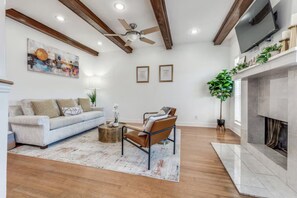 Ein Wohnzimmer mit Sofa, Sessel, Couchtisch, Kamin und Deckenventilator.