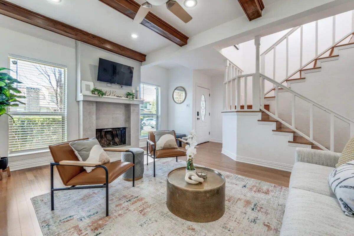 A spacious living room with a fireplace, a staircase, and a television mounted on the wall.