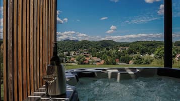 A hot tub with a view of a village and mountains in the background.