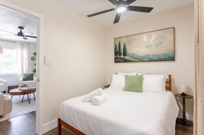 A hotel room with a bed, a ceiling fan, a painting, and a view of the outdoors. - Earthy Oasis: Private Pool, Putt Putt & Fire Pit (Largo)