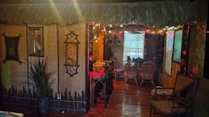 A traditional interior with a thatched roof, wooden walls, and a dining area with wicker furniture.