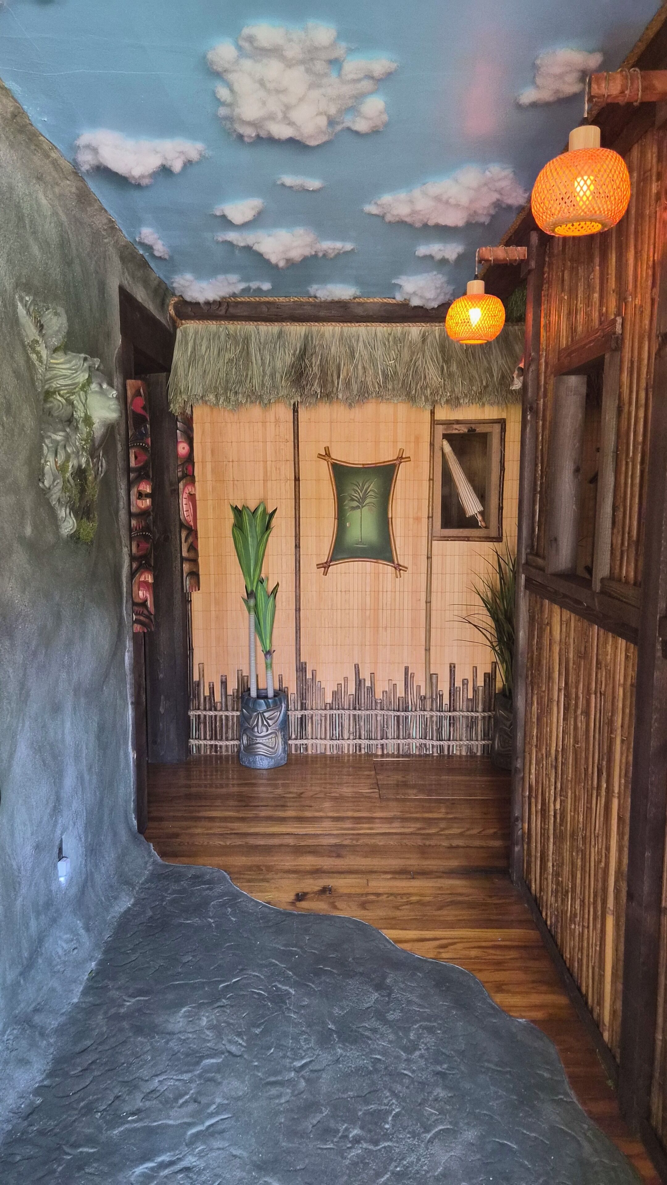 A narrow hallway with a wooden floor, a bamboo fence, and a ceiling mural.