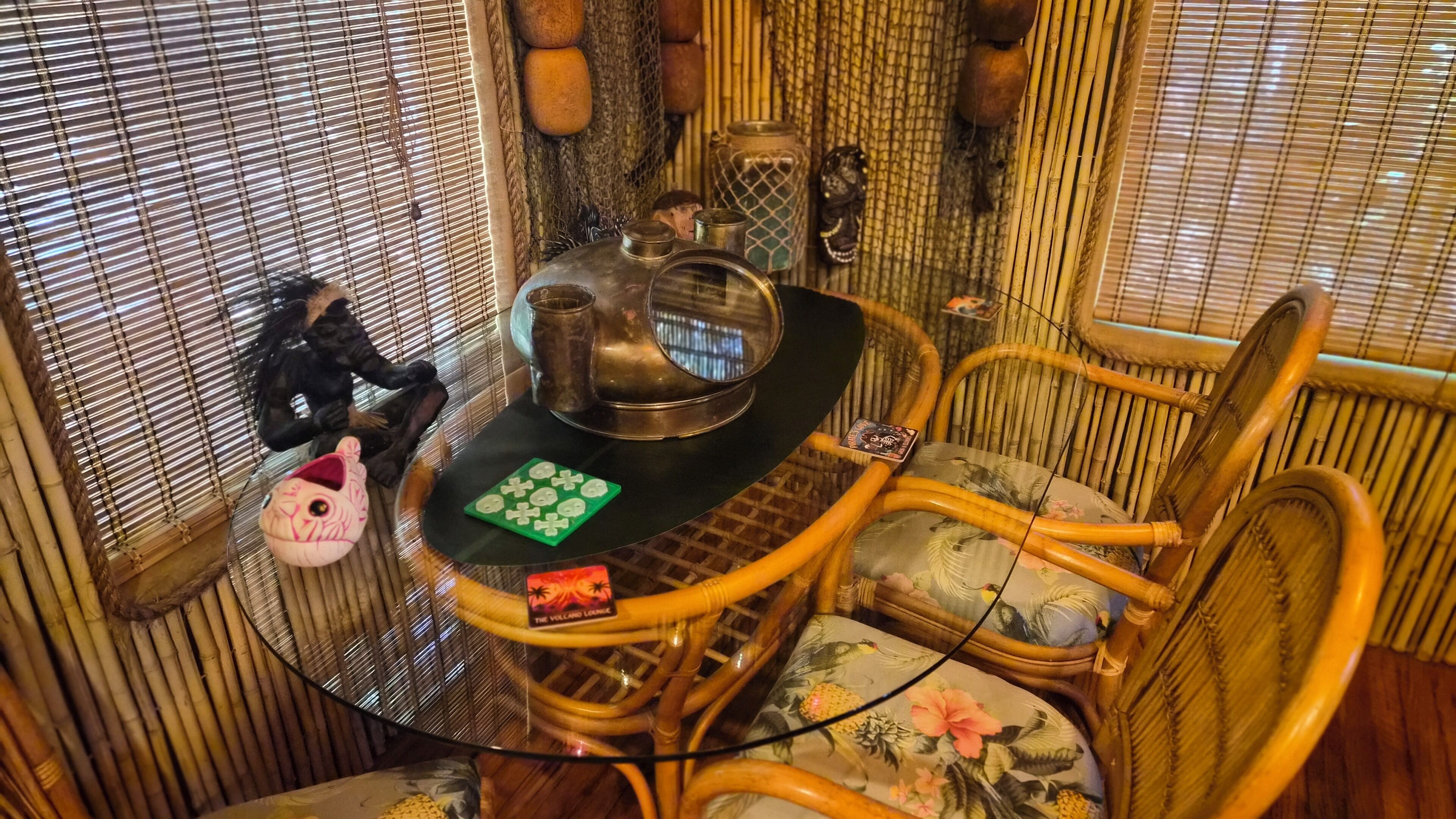 A room with a round table, wicker chairs, and a window with blinds.