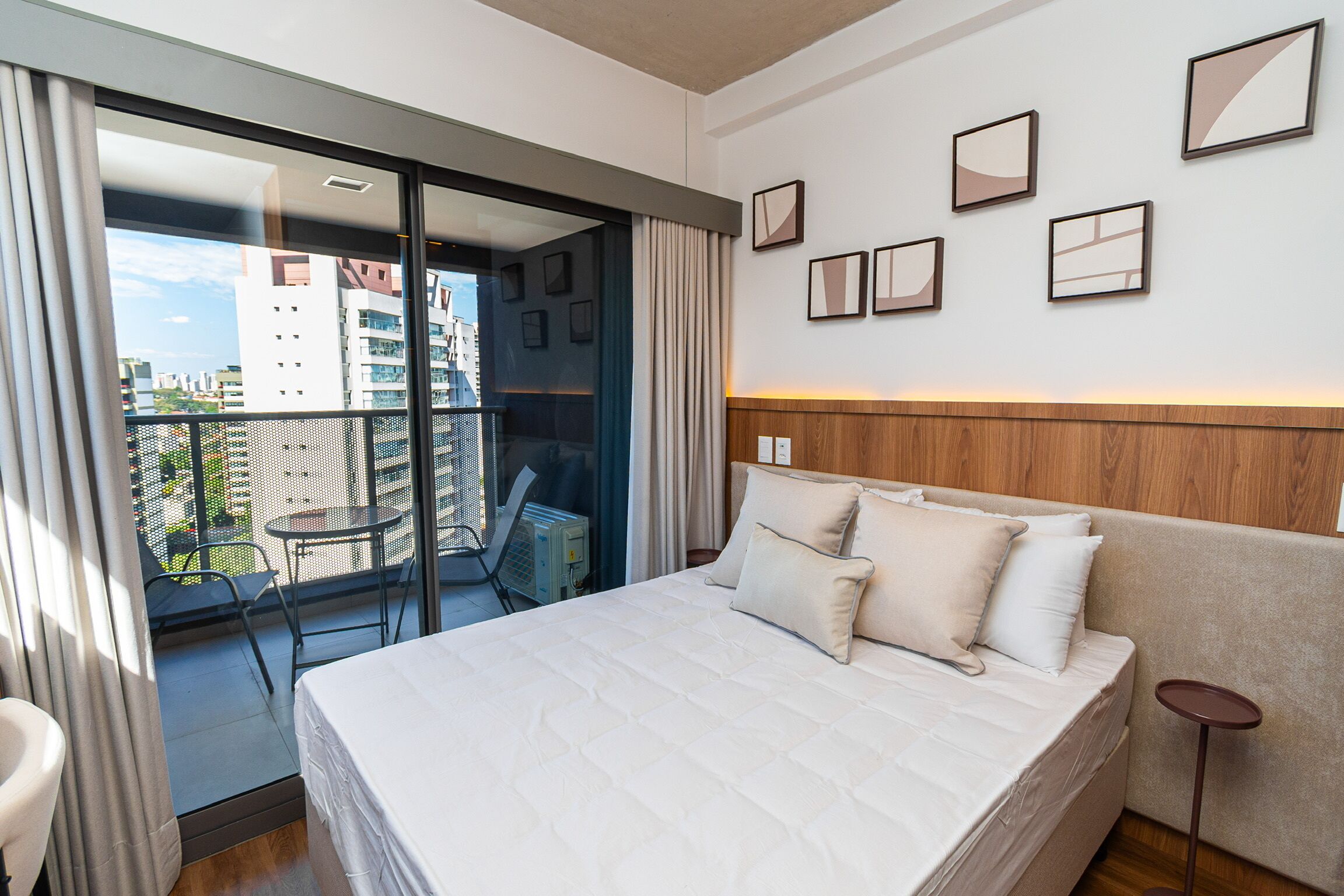 Ein Hotelzimmer mit einem großen Bett, einem Balkon mit Tisch und Stühlen sowie mehreren gerahmten Bildern an der Wand.