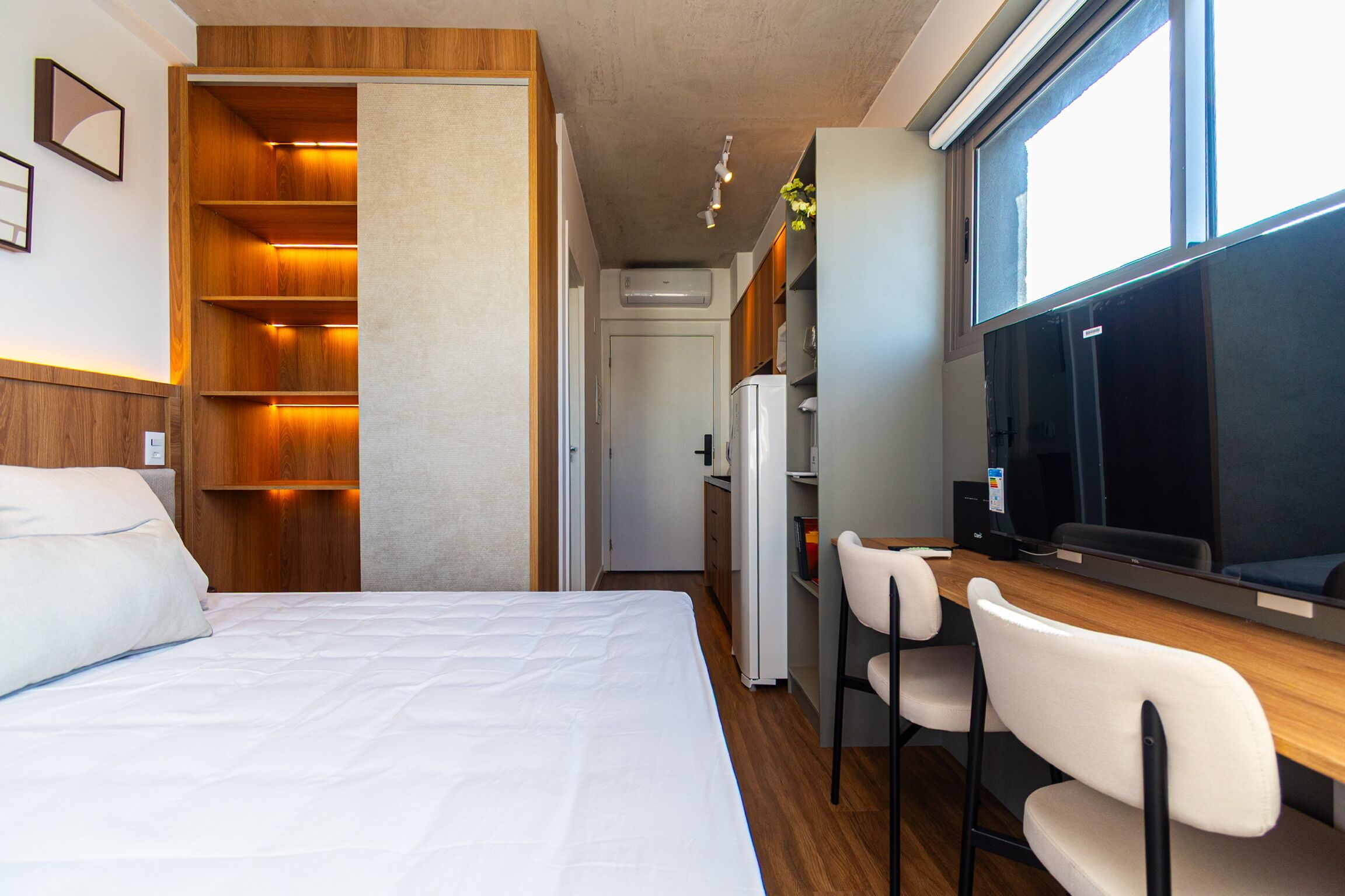 Une chambre d’hôtel comprenant un lit, un bureau avec un ordinateur, une télévision et une kitchenette.