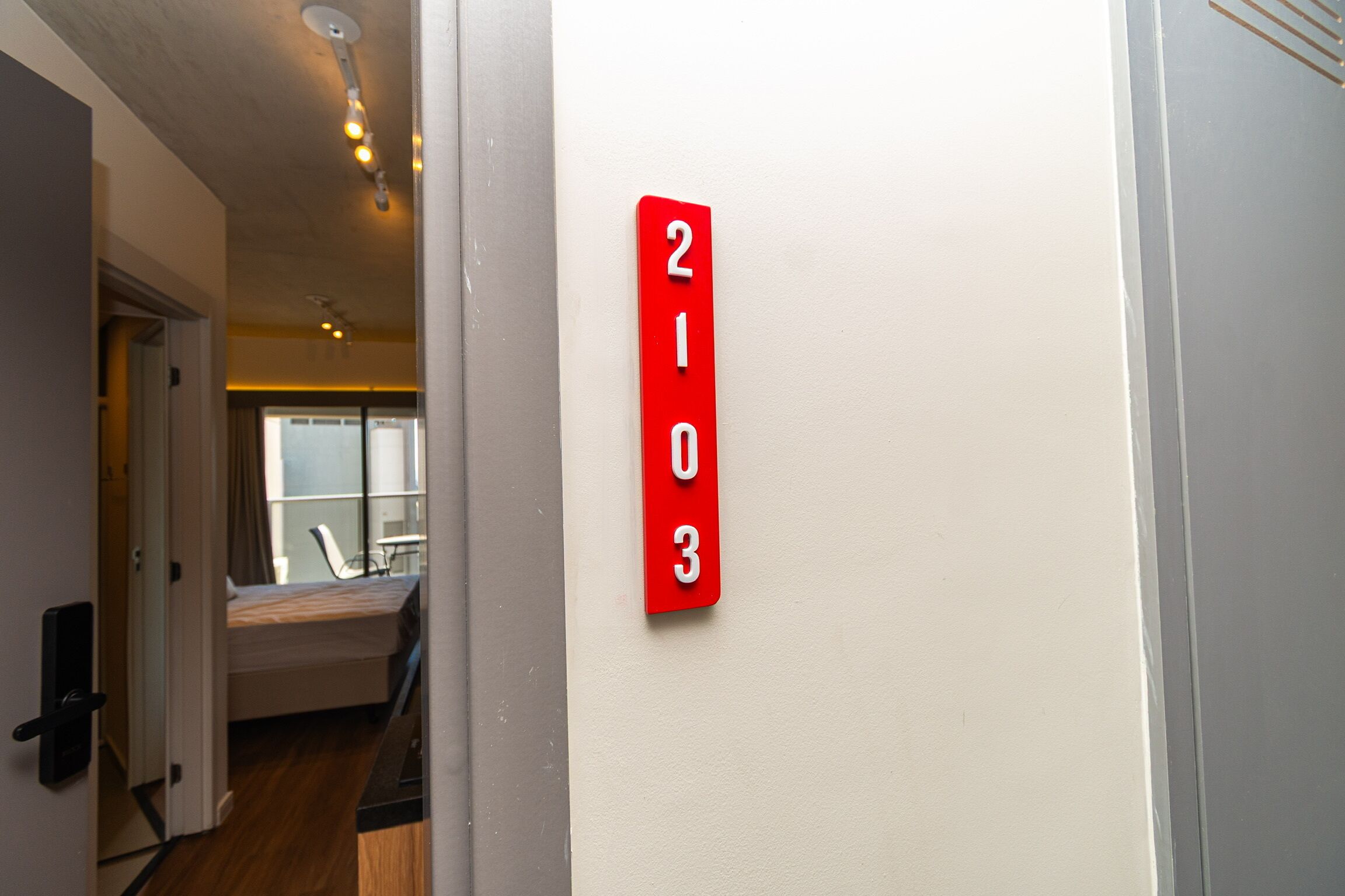 Un pasillo con una placa roja con el número de habitación 2103.
