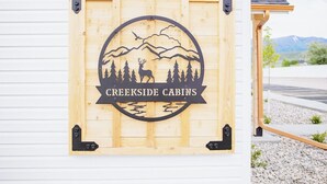 Un panneau en bois représentant la silhouette d’une montagne et d’un arbre, avec l’inscription « Creekside Cabins ».